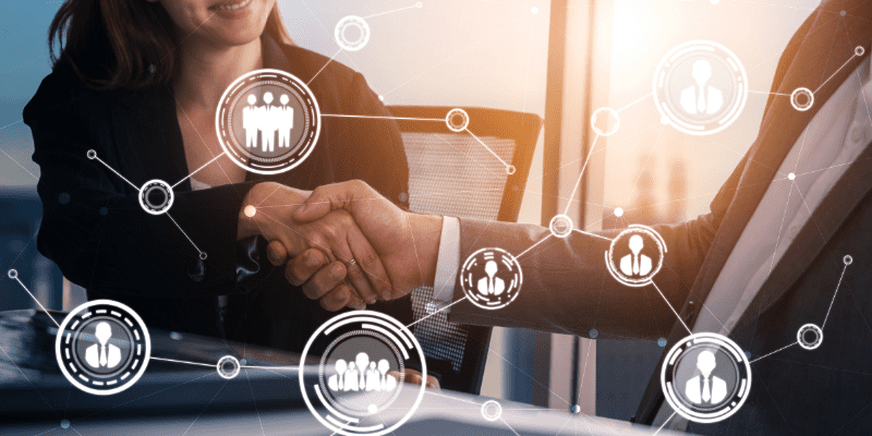 An image of a business women and business man shaking hands with technology graphics over it.