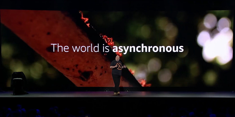 Werner Vogels stands in front of a screen that reads "The world is asynchronous."
